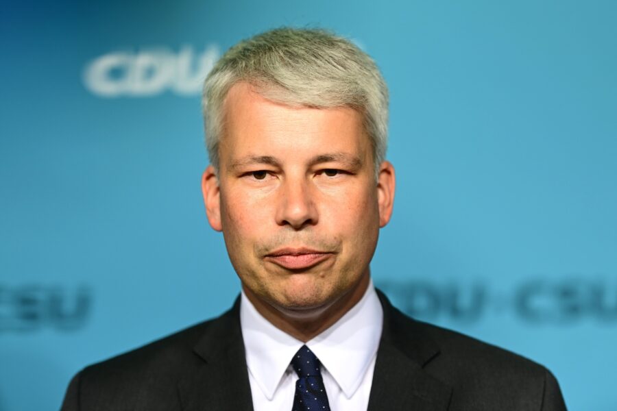 Ein Mann in Anzug vor blauem Hintergrund mit unscharfem Schriftzug "CDU-CSU".