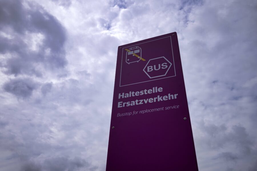 Lila Schild mit Aufschrift: "Haltestelle Ersatzverkehr". Bewölkter Himmel im Hintergrund.