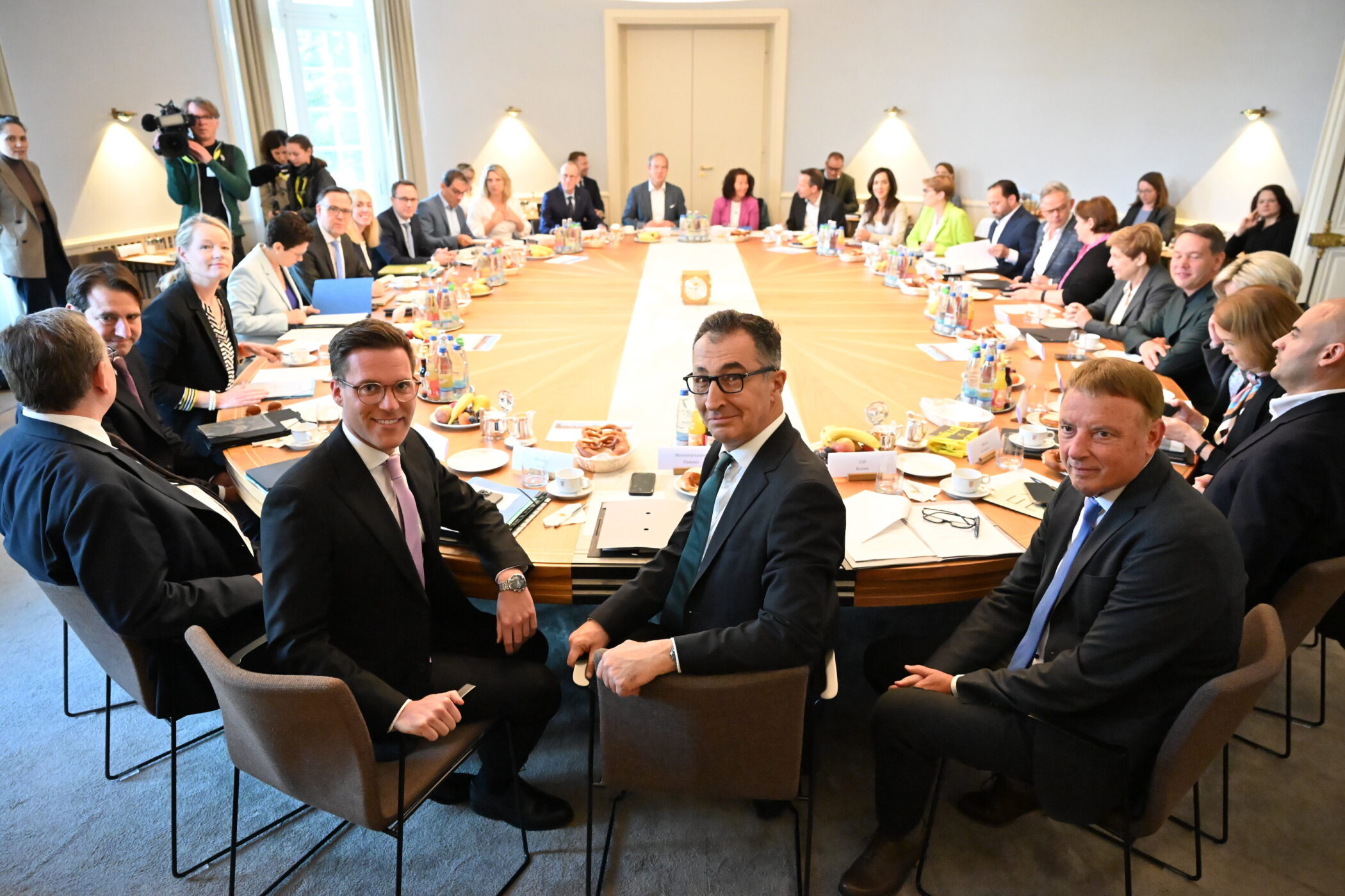 Viele Menschen sitzen an einem großen rechteckigen Konferenztisch.