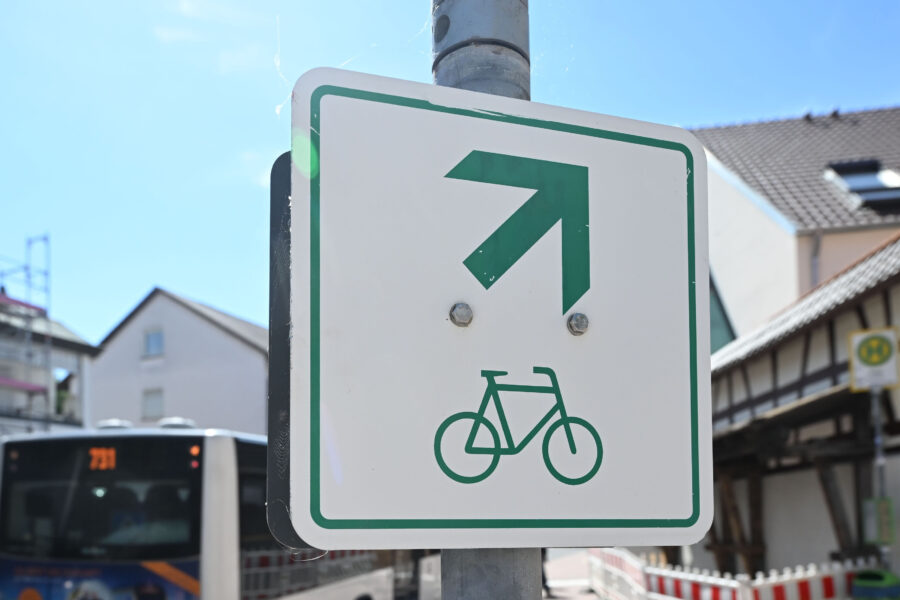 Schild mit Fahrrad und grünem Pfeil nach rechts oben auf einem Pfosten.