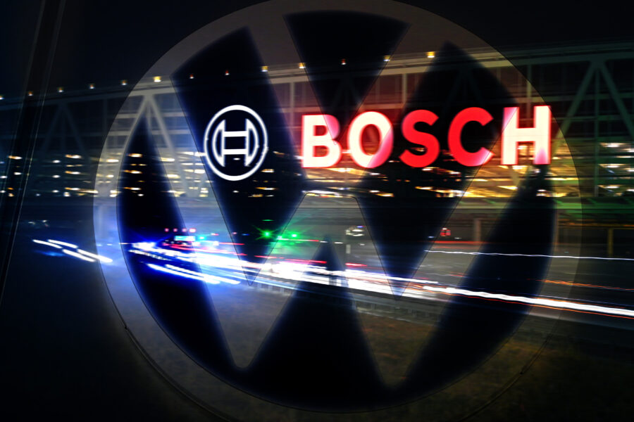 Logo von VW und Bosch, Hintergrund unscharfe Lichter, rote und weiße Lichtspuren.