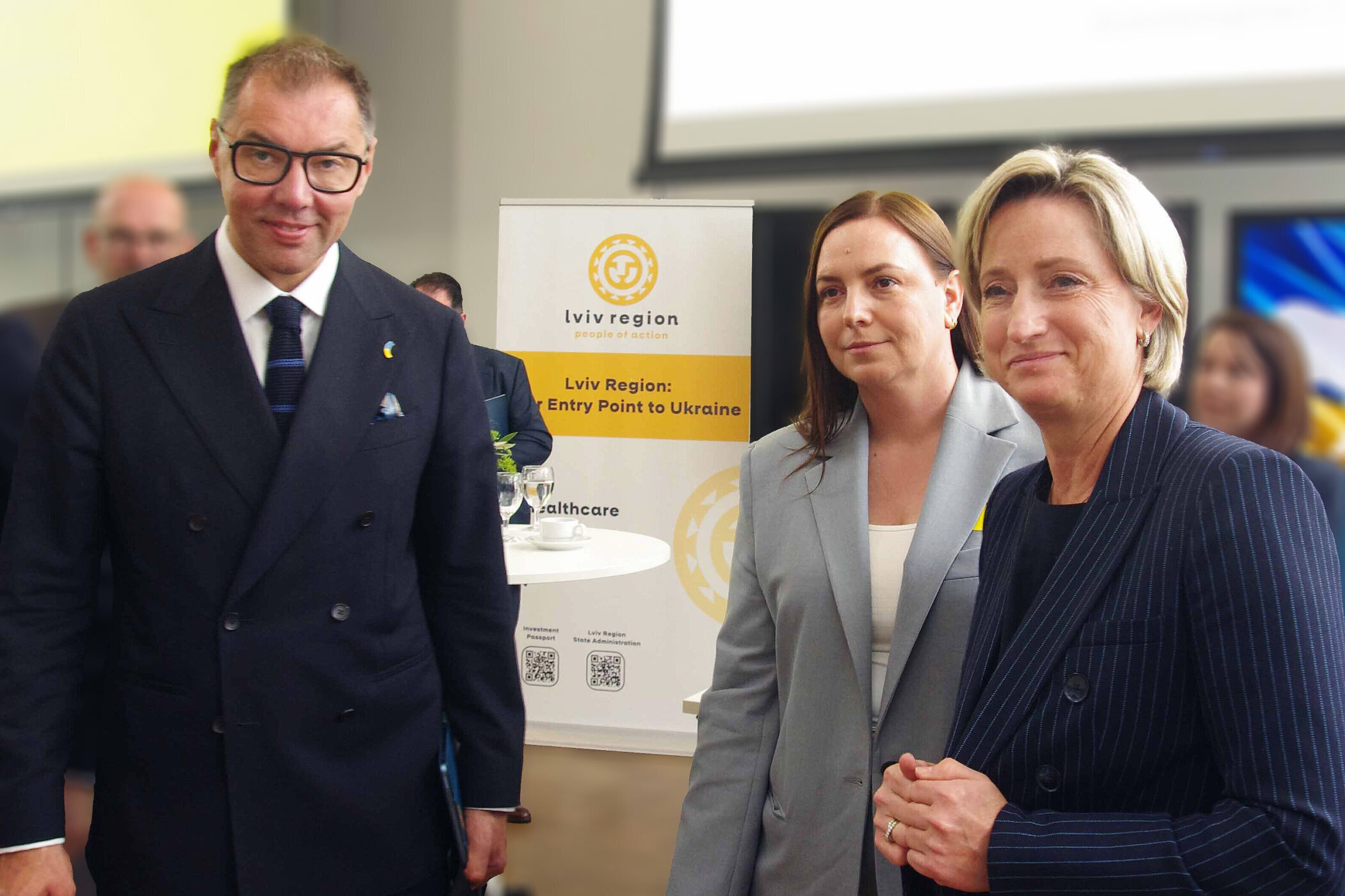 Drei Personen stehen vor einem Banner mit der Aufschrift "Lviv Region".