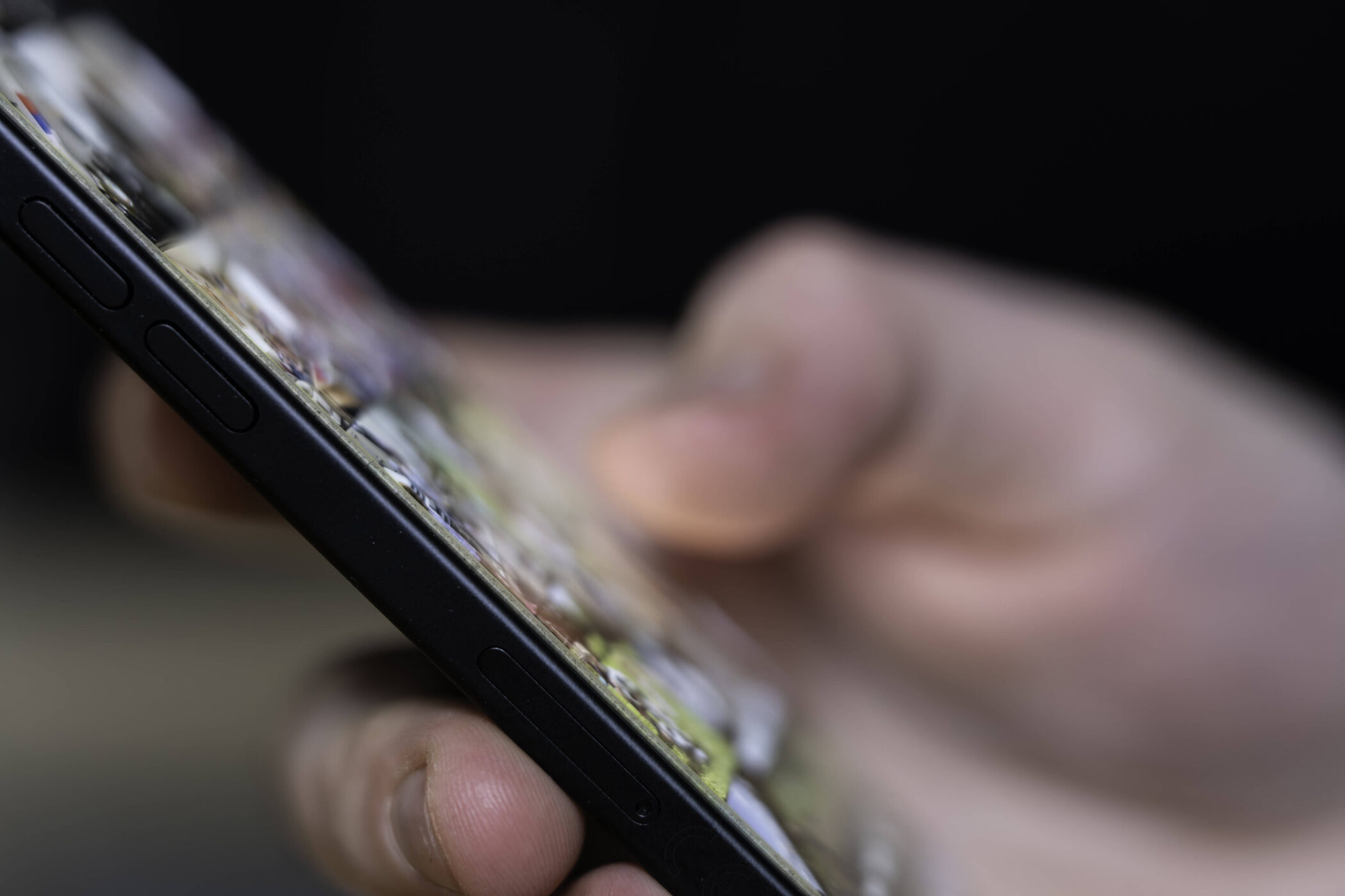 Person hält ein Smartphone in der Hand, Fokus auf die seitlichen Tasten.