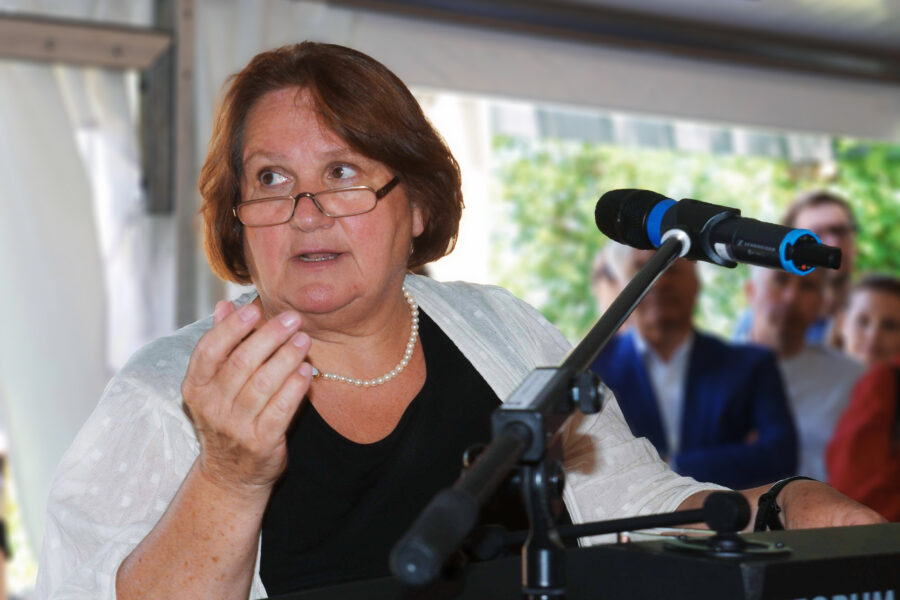 Frau am Mikrofon spricht vor Publikum. Textausschnitt: "FORUM".