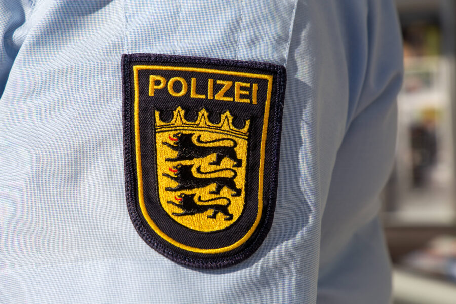 Polizeiuniform mit Wappen und drei schwarzen Löwen auf gelbem Hintergrund.