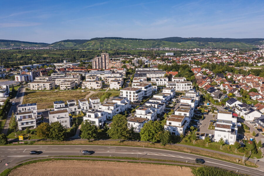 Luftaufnahme einer Wohnsiedlung mit weißen Häusern und einer Straße im Vordergrund.