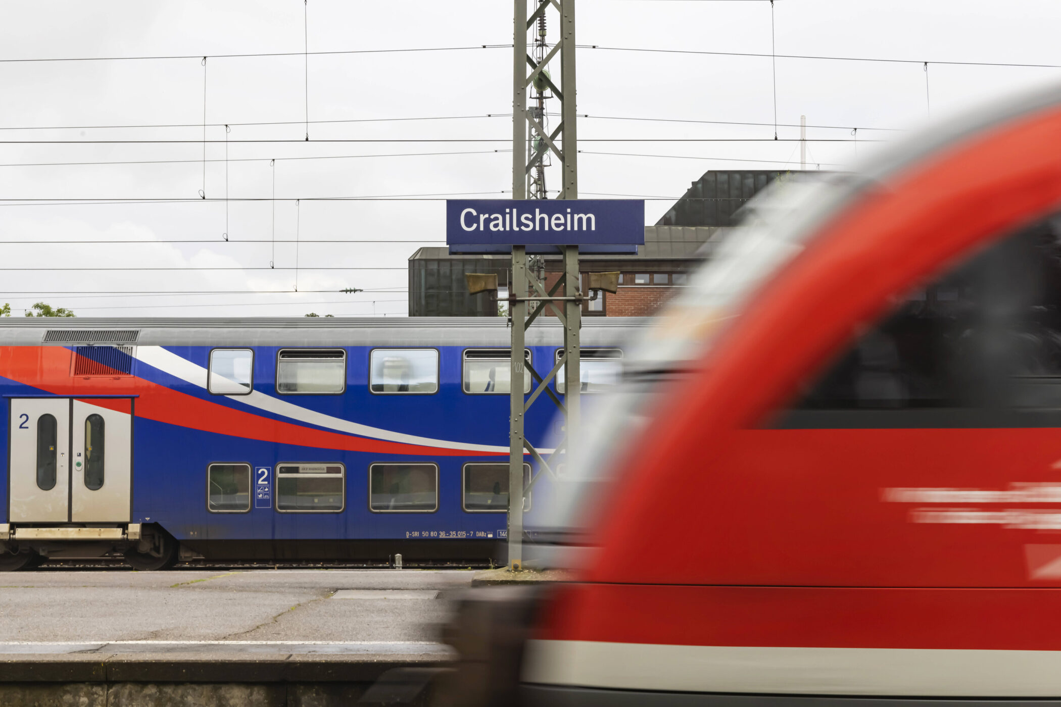 Zwei Züge an einem Bahnhof; Schild mit "Crailsheim".