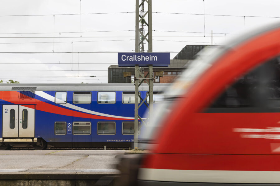 Zwei Züge an einem Bahnhof; Schild mit "Crailsheim".