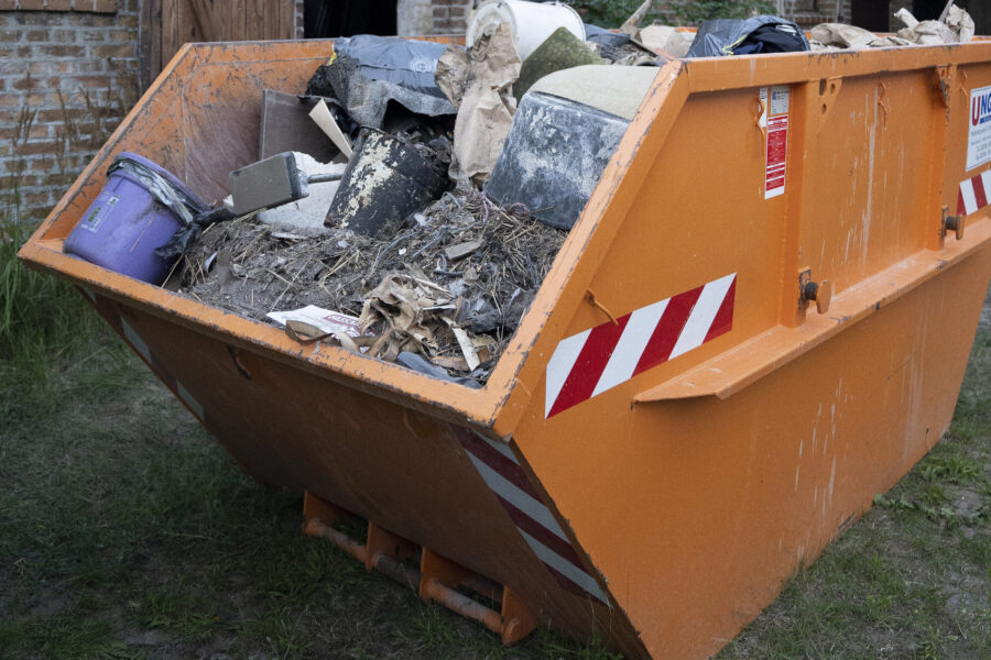 Oranger Container voller Bauschutt und Abfall, im Freien.