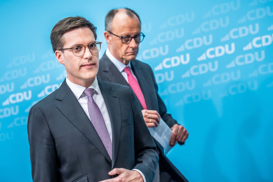 Zwei Männer in Anzügen vor blauem Hintergrund mit CDU-Logo.