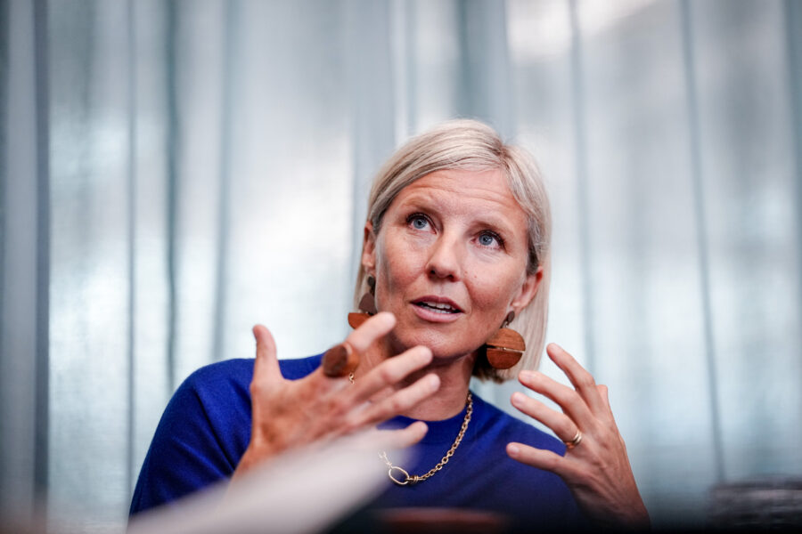 Eine Frau gestikuliert mit den Händen vor einem unscharfen Hintergrund.