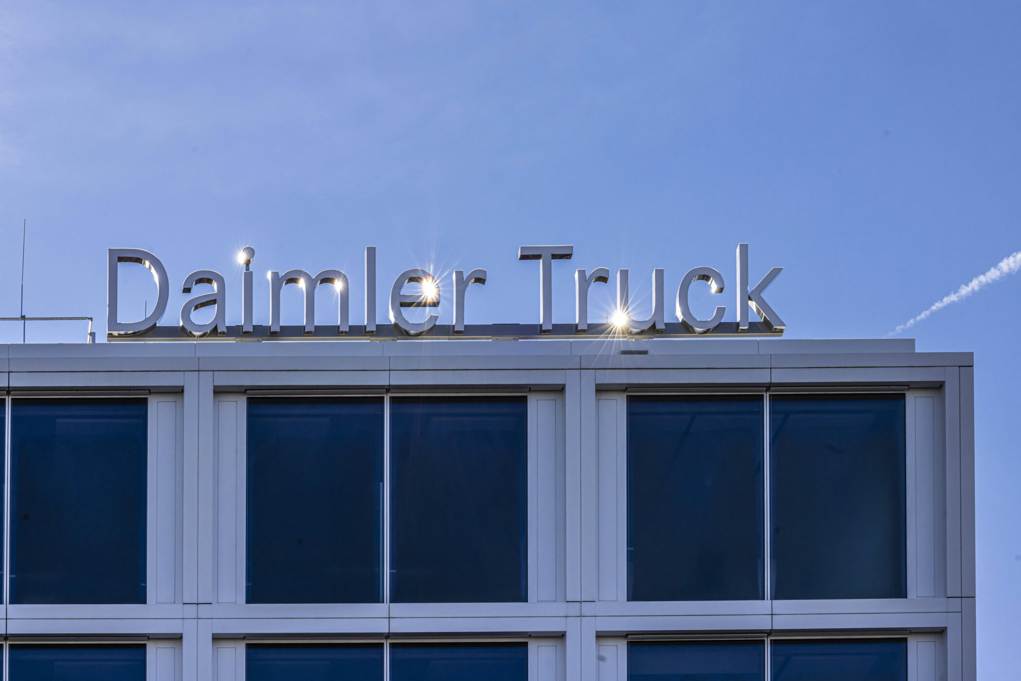 Dach eines Gebäudes mit Schriftzug "Daimler Truck" vor blauem Himmel.