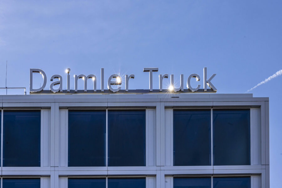 Dach eines Gebäudes mit Schriftzug "Daimler Truck" vor blauem Himmel.