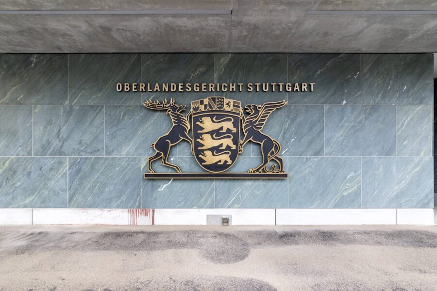 Wand mit Schild und Text „Oberlandesgericht Stuttgart“, darunter Wappen mit Hirsch.