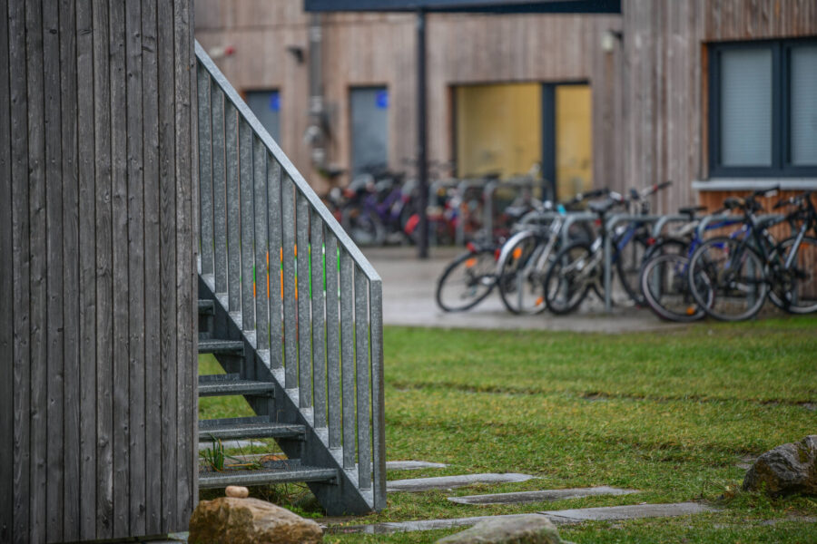 Treppe neben Holzwand, im Hintergrund viele Fahrräder an Ständern.