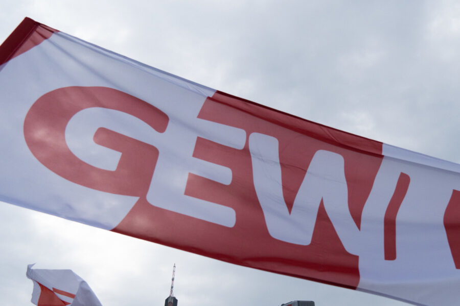 Weiße Fahne mit rotem GEW-Logo, Himmel im Hintergrund.
