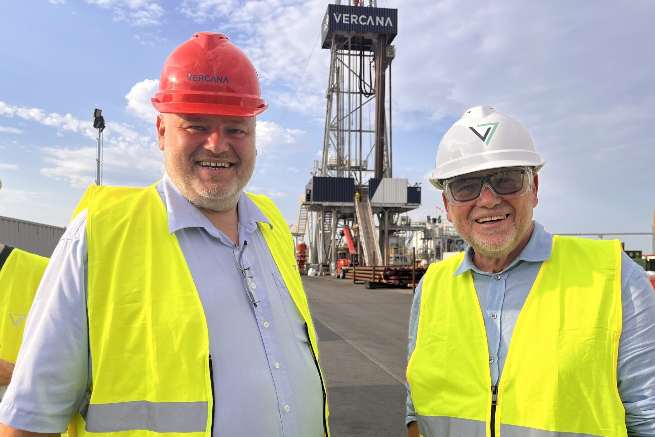 Zwei Männer mit Schutzhelmen und Warnwesten vor einer Industrieanlage.