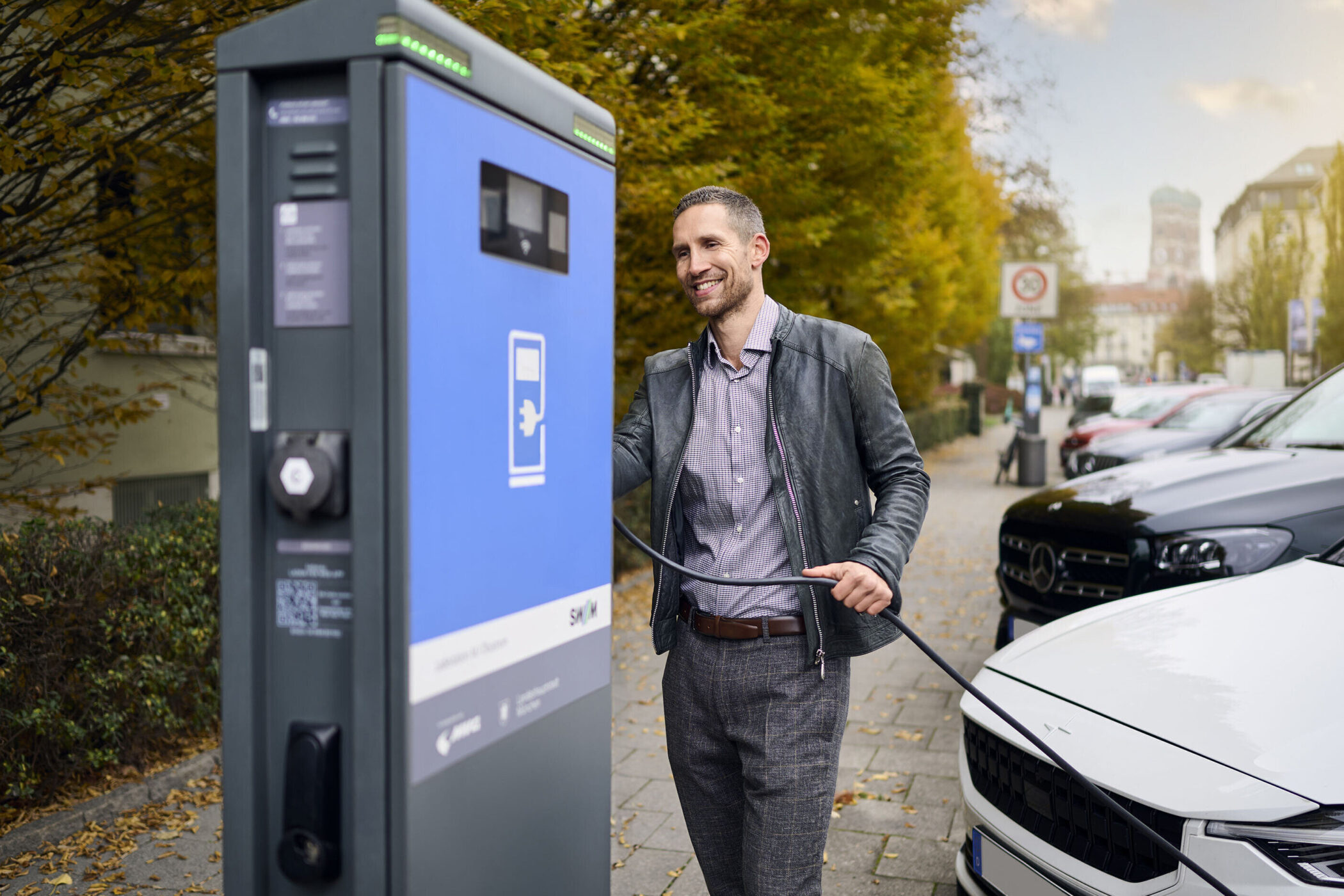 Ein Mann lädt ein Elektroauto an einer Ladestation im Freien auf.