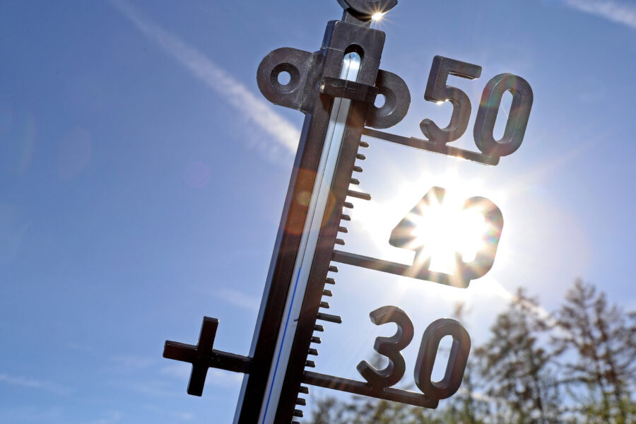 Thermometer mit Sonne, zeigt 30 bis 50 Grad, blauer Himmel im Hintergrund.
