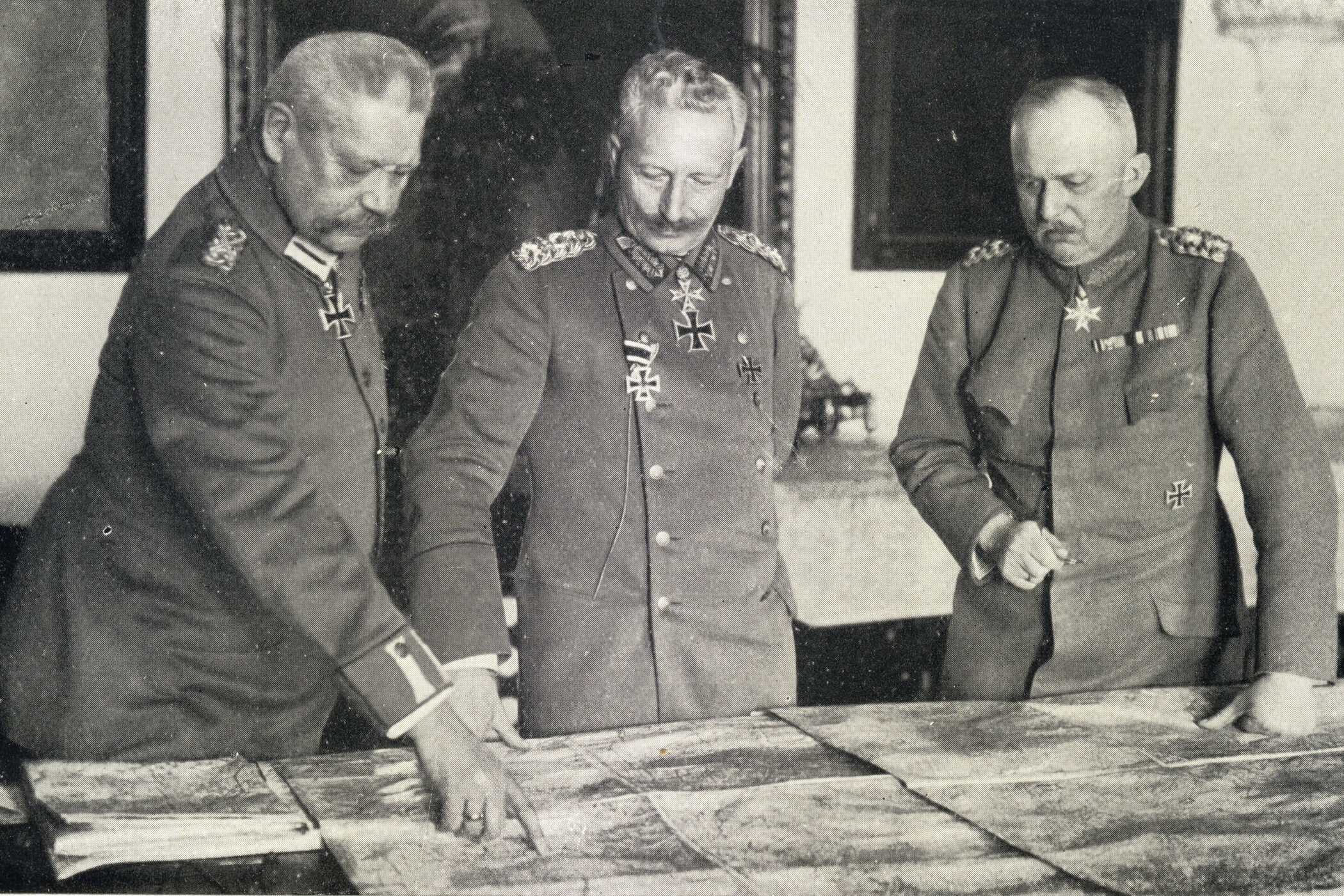 Drei Männer in Uniformen studieren eine große Landkarte.