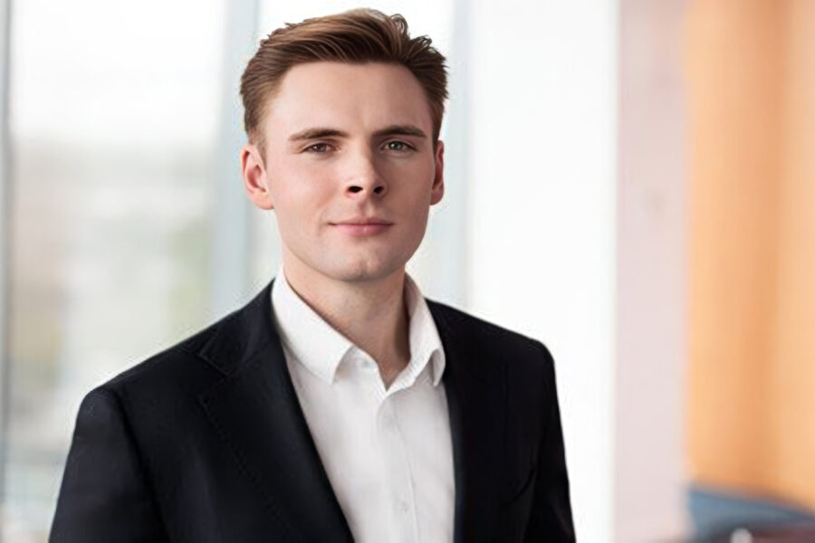 Eine Person in Anzug vor unscharfem Hintergrund.