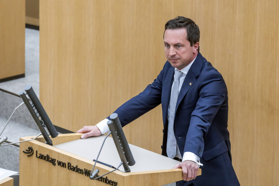 Mann im Anzug steht an einem Rednerpult im Landtag von Baden-Württemberg.