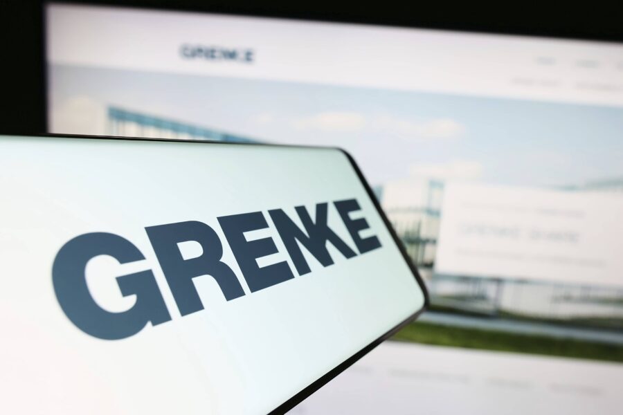 Text "GRENKE" groß auf einem Bildschirm, unscharfer Hintergrund.