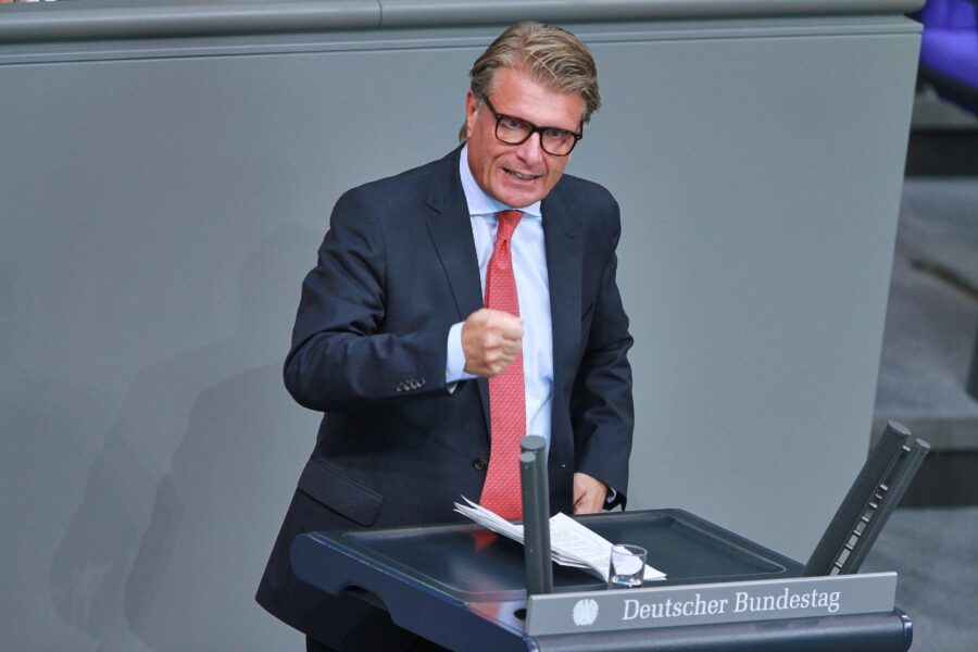 Ein Mann im Anzug spricht an einem Rednerpult mit Aufschrift "Deutscher Bundestag".
