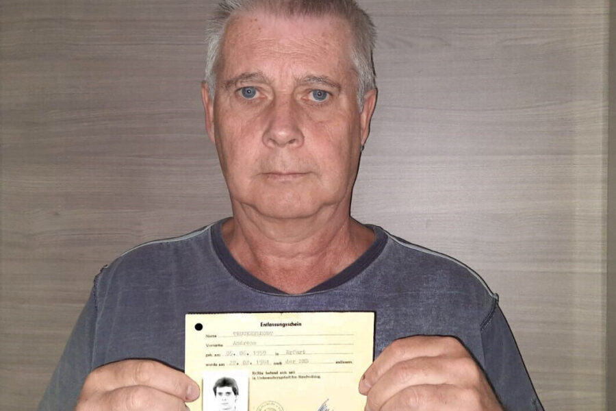Älterer Mann hält ein Dokument mit einem kleinen Foto in der Hand.