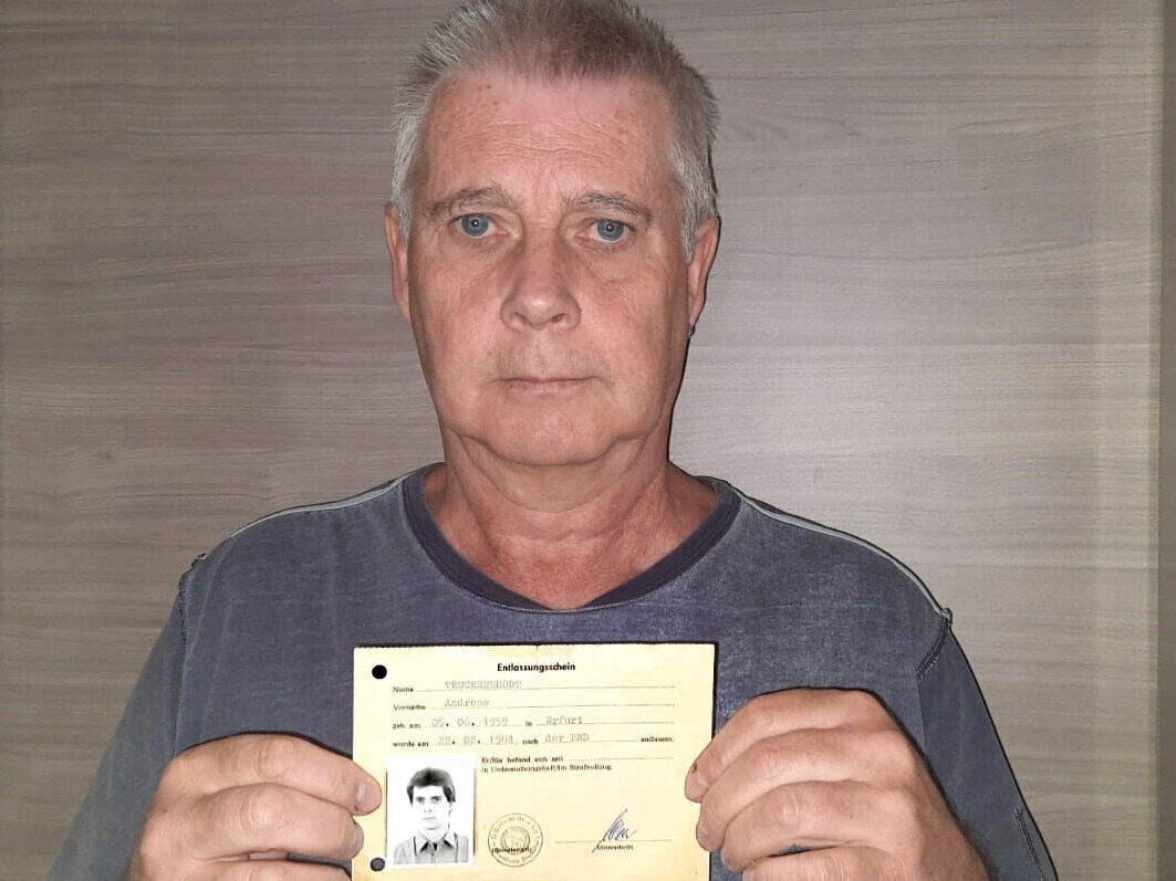 Älterer Mann hält ein Dokument mit einem kleinen Foto in der Hand.