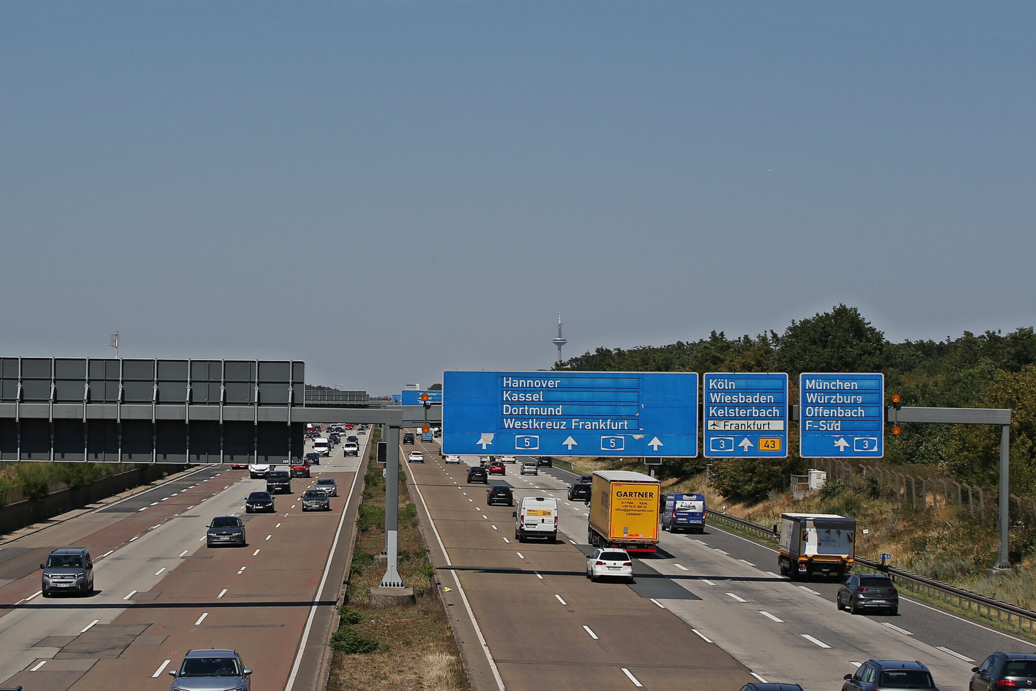 Autobahn mit Verkehrszeichen zu Hannover, Kassel, Dortmund, Köln, München, sechsspurig.