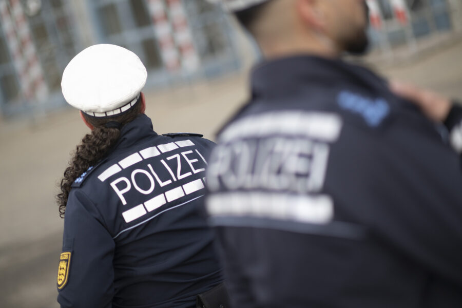 Zwei Polizisten in Uniform, Rückenansicht, "POLIZEI" auf Jacken.