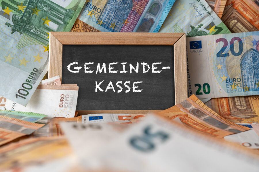 Tafel mit „Gemeindekasse“ umgeben von Euro-Banknoten.