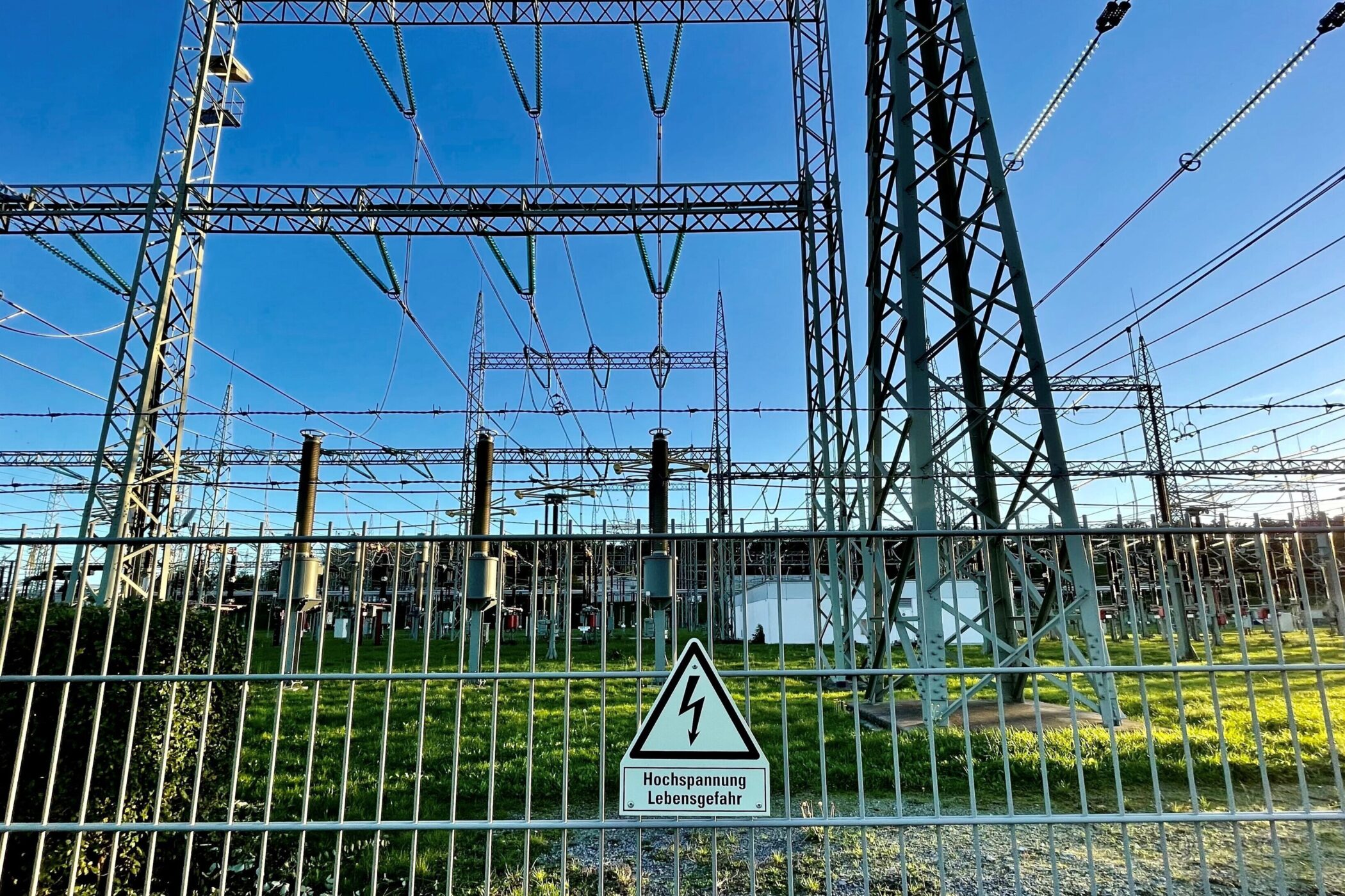 Umspannwerk hinter Zaun mit Warnschild "Hochspannung Lebensgefahr".
