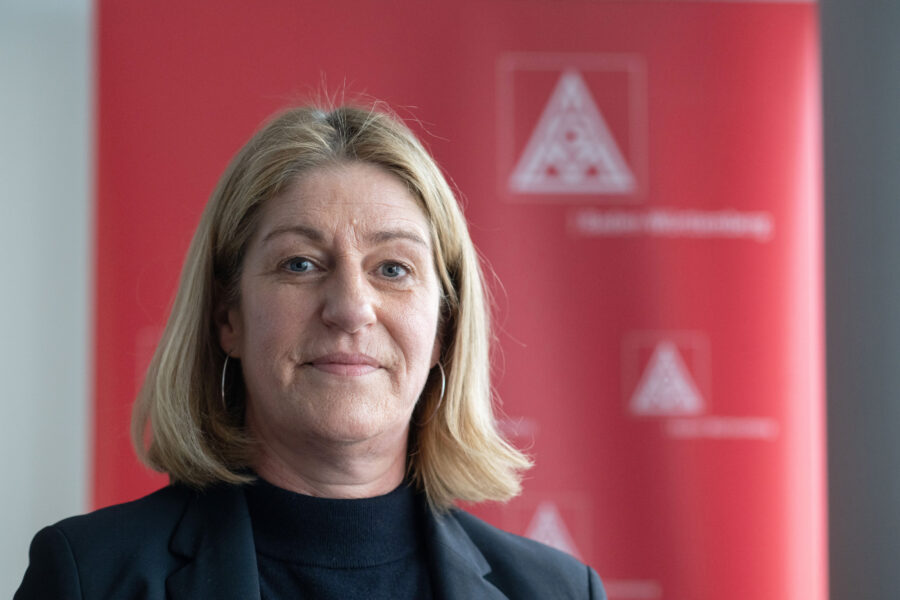 Eine Frau vor einem roten Hintergrund mit einem weißen Logo.