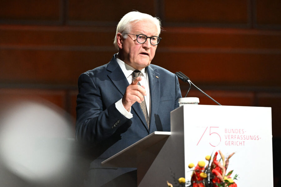 Mann am Rednerpult, Anzug tragend, spricht zu Publikum. Text: "75 Bundesverfassungsgericht".