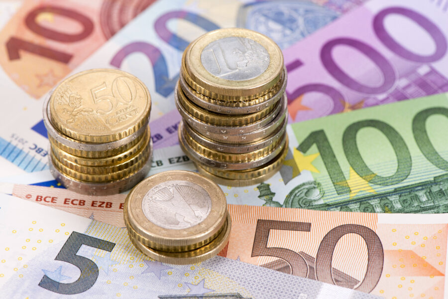 Euromünzen auf fächerförmig gelegten Euroscheinen verschiedener Werte.