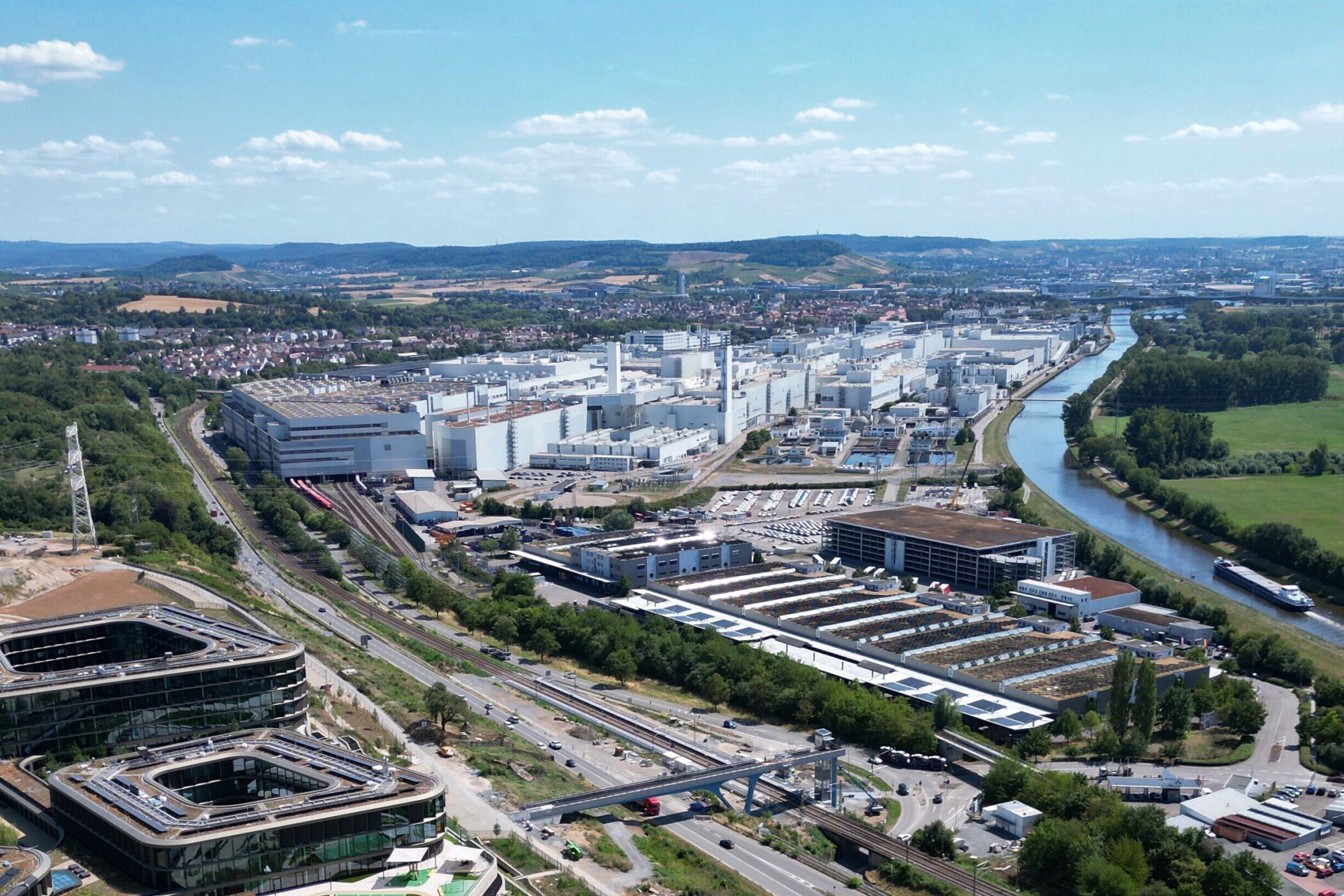 Industrieanlage und Fluss, umliegende Landschaft mit Feldern und Siedlungen.