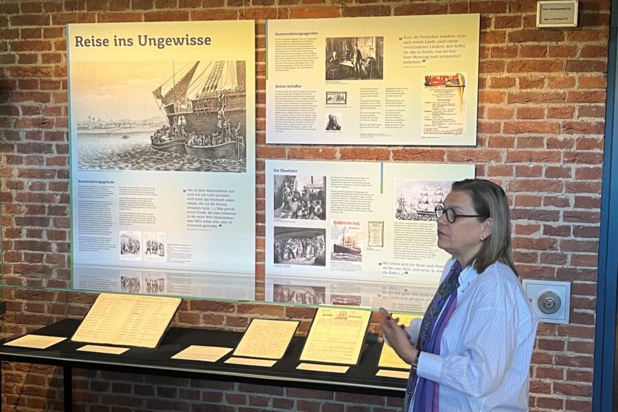 Eine Frau steht vor einer Ausstellung mit Schautafeln und alten Dokumenten.