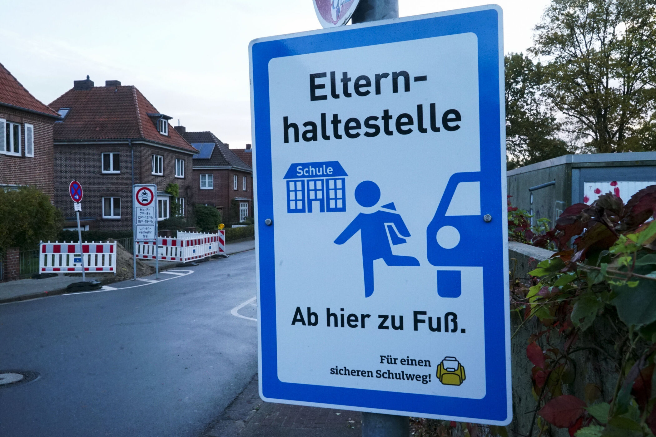 Schild mit Text: "Elternhaltestelle. Ab hier zu Fuß. Schule."