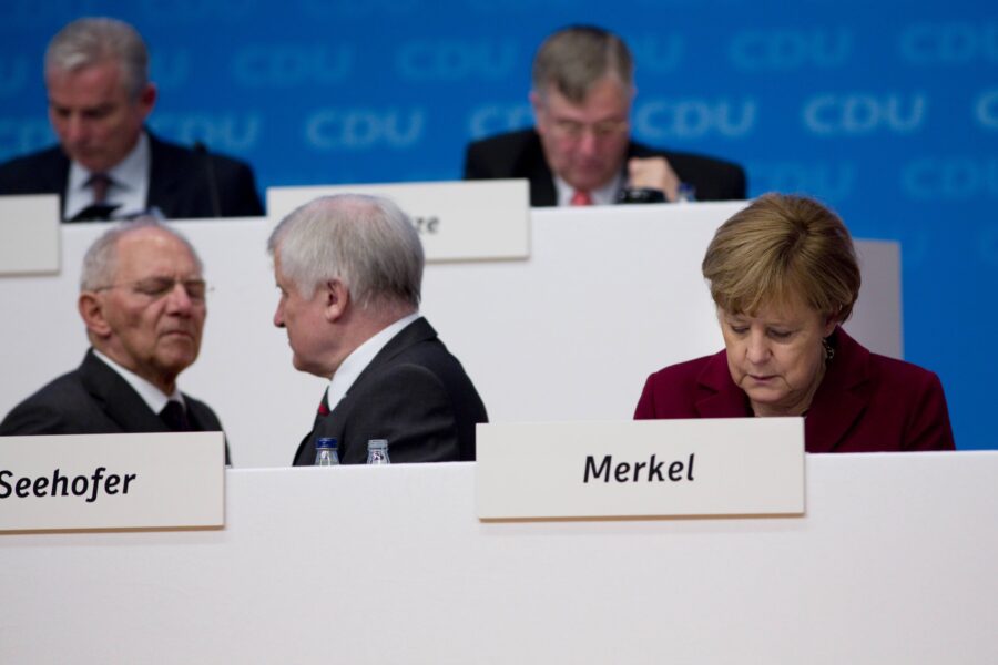 Fünf Personen unter Namensschildern. Text: Seehofer, Merkel, CDU-Hintergrund.
