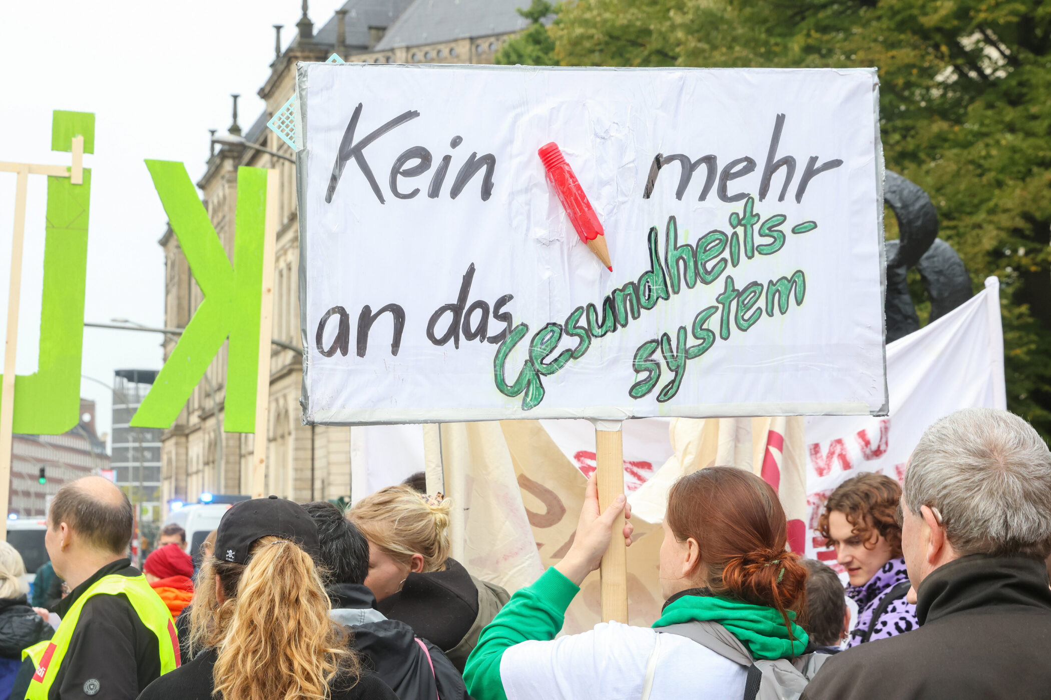 Personen bei einer Demo mit einem Schild: „Kein mehr an das Gesundheitssystem“.