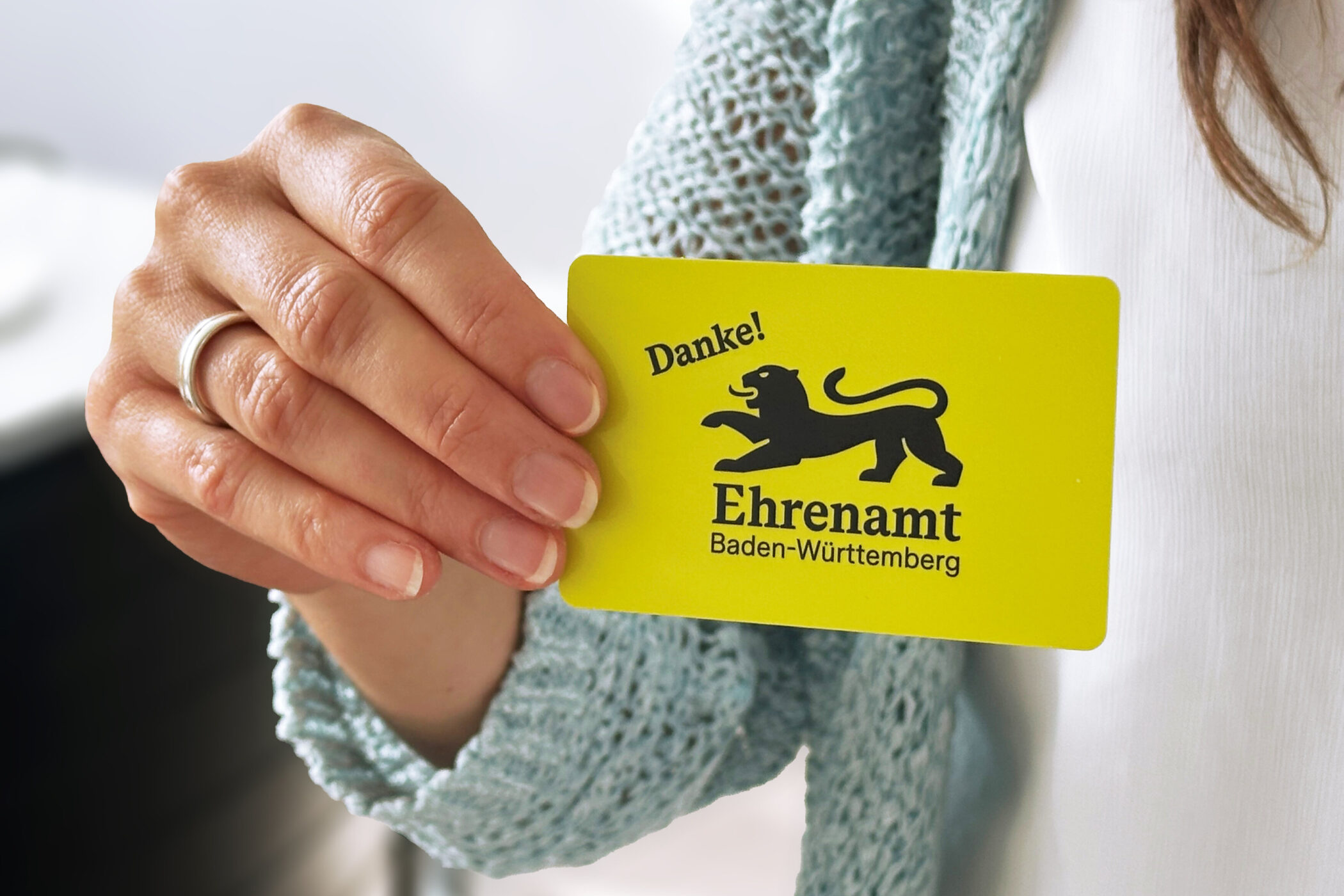 Hand hält gelbe Karte mit Löwen-Logo, Aufschrift: "Danke! Ehrenamt Baden-Württemberg".