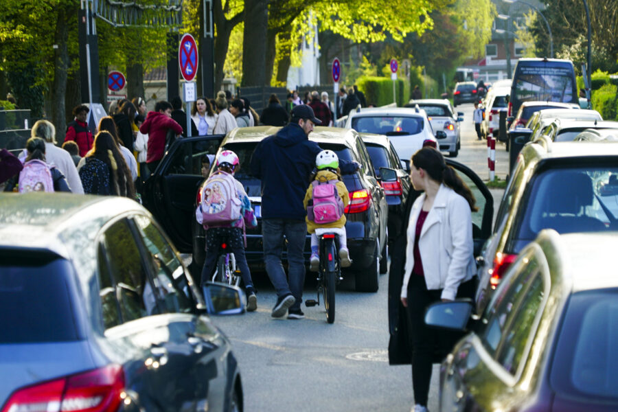 Verkehr überfüllte Straße, Menschen mit Fahrrädern, geparkte Autos, Durchfahrtsverbotsschilder.