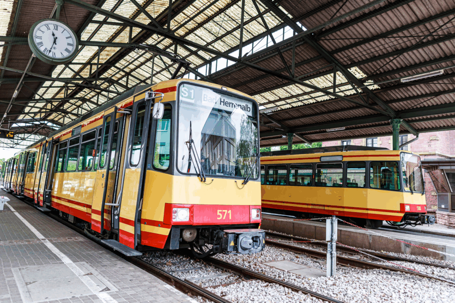 Zwei gelbe Straßenbahnen im Bahnhof unter einem Uhrendach.