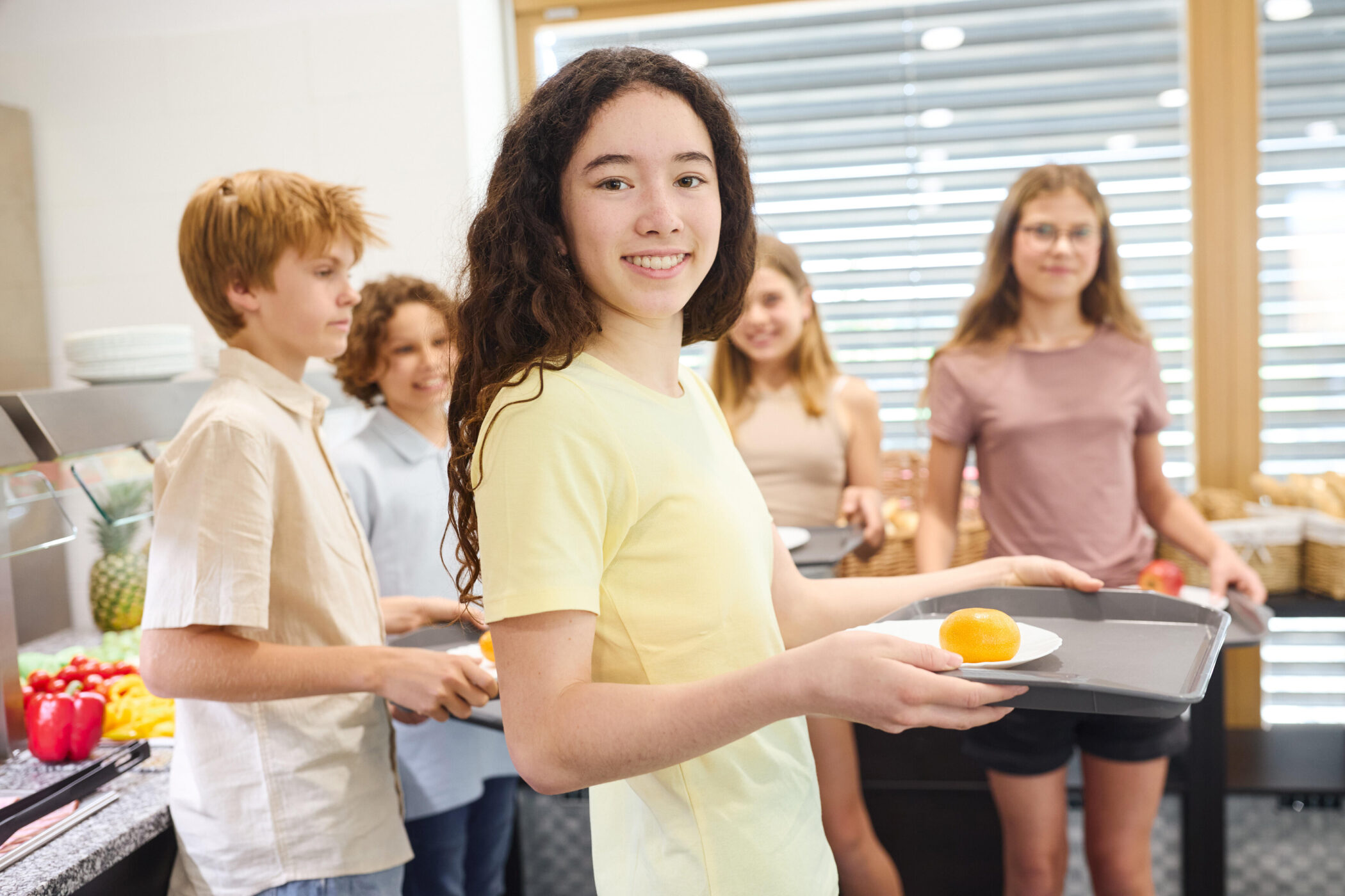 Fünf Jugendliche stehen in einer Kantine mit Tabletts.