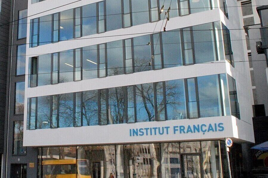 Mehrstöckiges Gebäude mit Schriftzug "INSTITUT FRANÇAIS". Glasfassaden spiegeln Bäume.