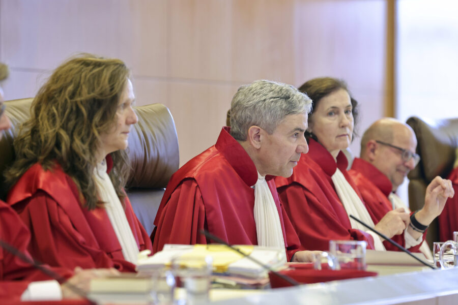 Fünf Personen in roten Roben sitzen an einem Tisch mit Akten.
