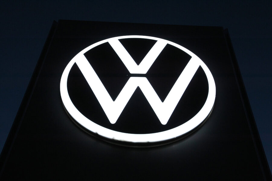 Weiß leuchtendes VW-Logo auf dunklem Hintergrund.