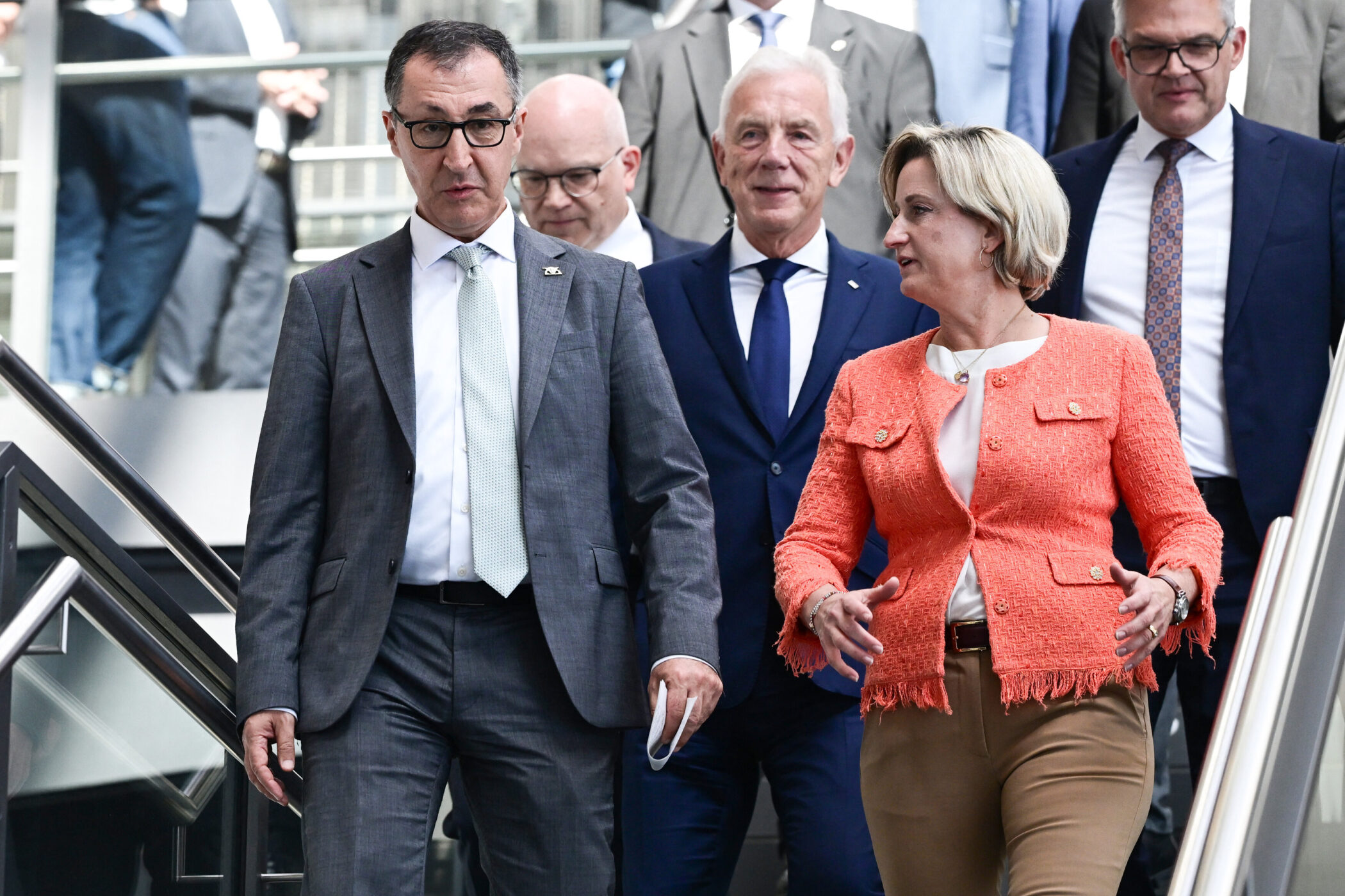 Sechs Personen in Anzügen gehen eine Treppe hinunter.
